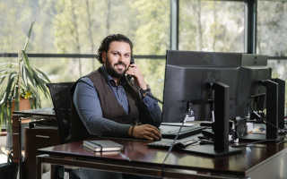 Freudlicher Mitarbeiter in modernem Büro beim Telefonieren