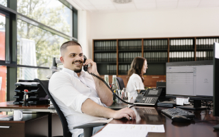 Freudlicher Mitarbeiter in modernem Büro beim Telefonieren